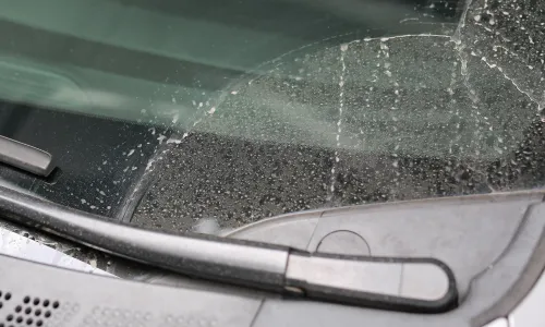 車のフロントガラスに付着した白い水垢