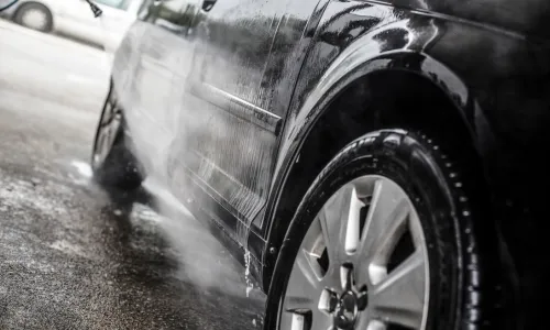 高圧洗浄機で黒い車のボディを洗車している様子